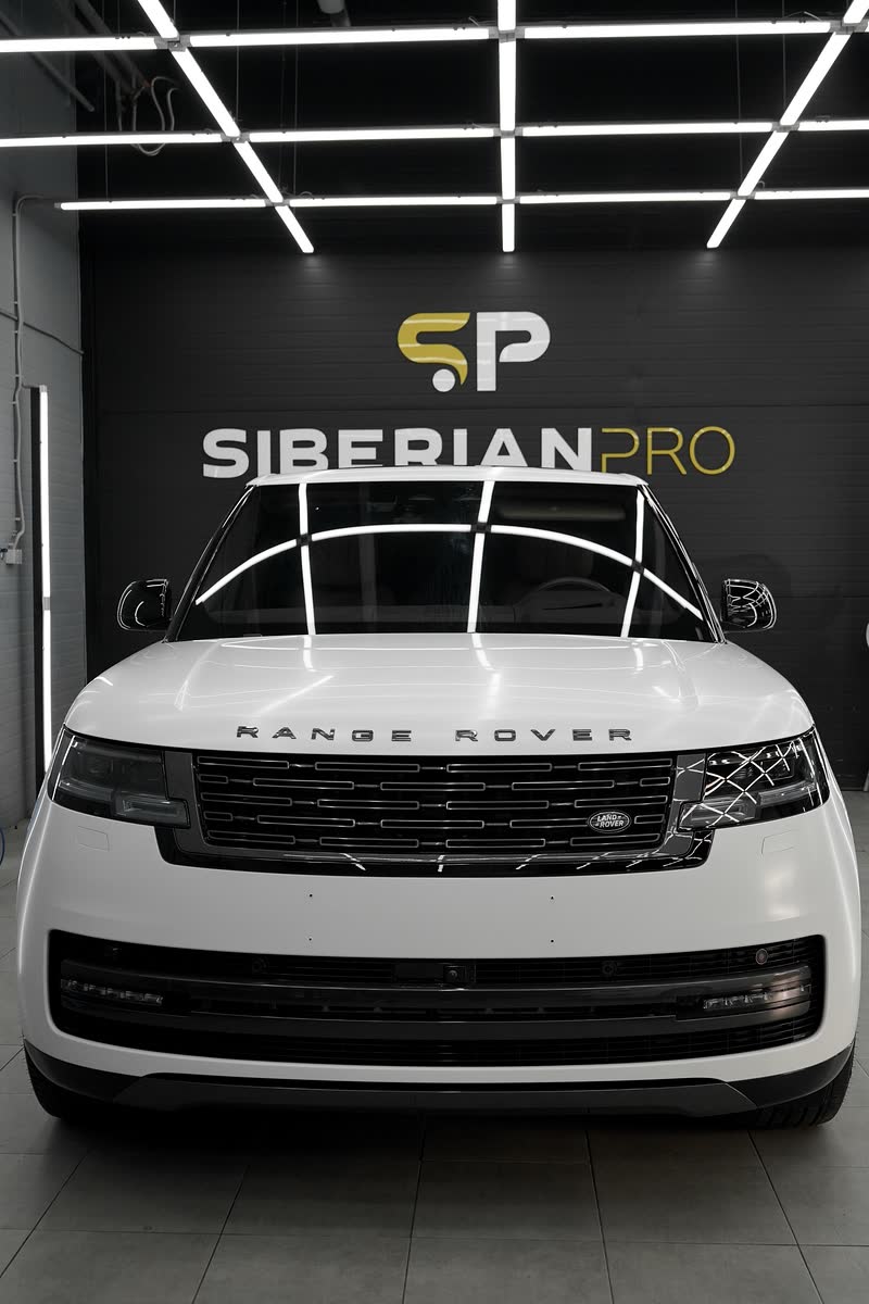 Белый Range Rover перед стеной с логотипом Siberianpro