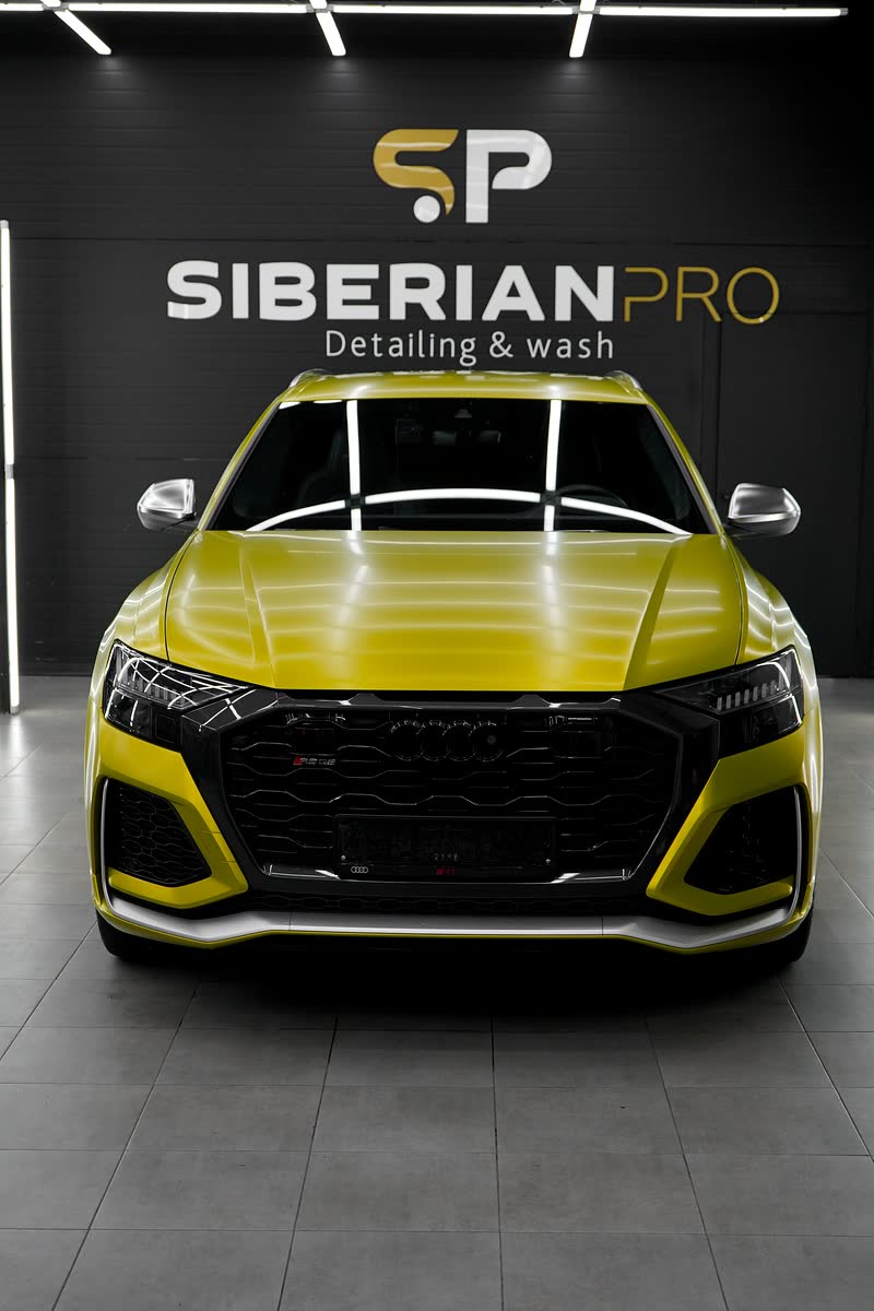 Жёлтая Audi RS Q8 перед логотипом студии