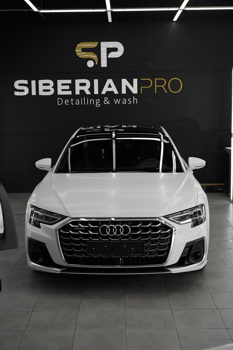 Белая Audi A8 перед логотипом Siberianpro