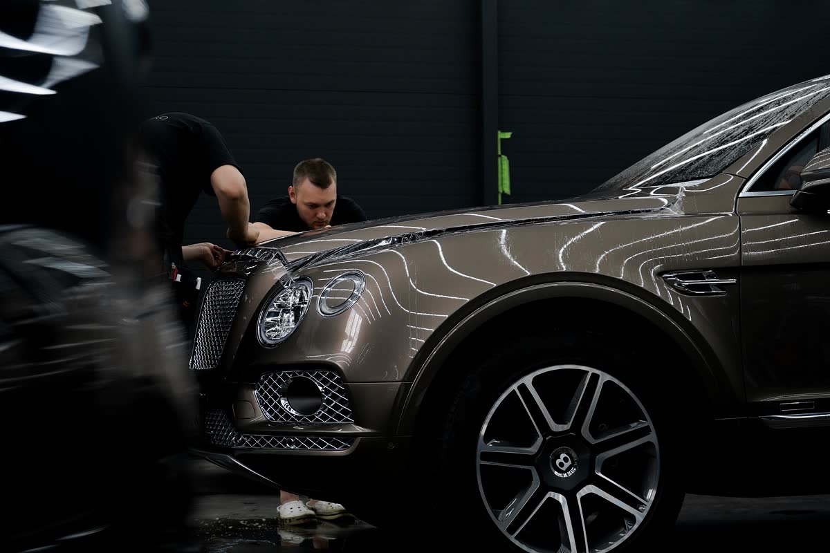 Двое мастеров оклеивают Bentley Bentayga