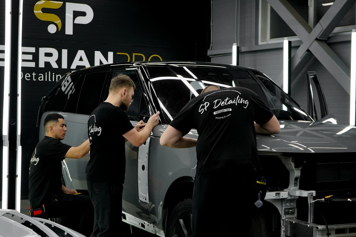 Двое мастеров оклеивают Range Rover